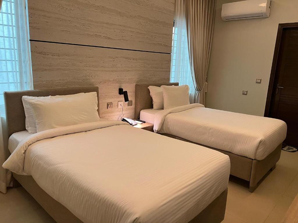 two beds in a hotel room with white sheets at Heritage Heaven by Premium Suites in Karachi