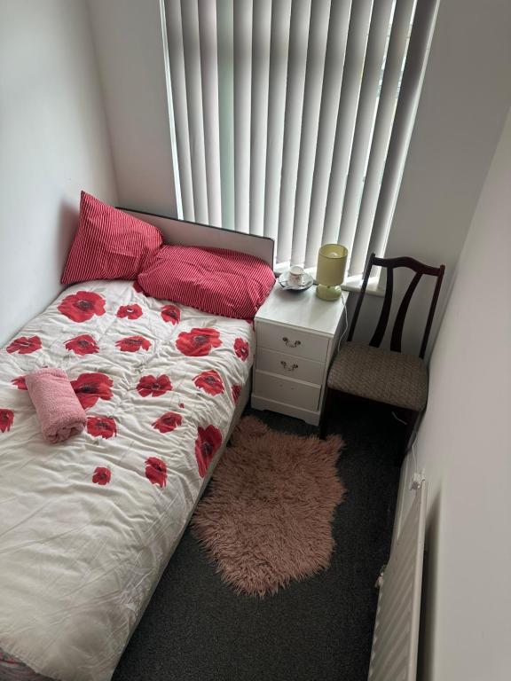 a bedroom with a bed with red roses on it at Quiet room 5 in Coventry