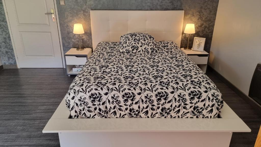 a large bed with a black and white comforter at Gerlande 2 in Bourg-Argental