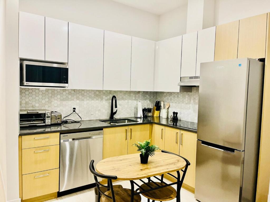 a kitchen with a table and a stainless steel refrigerator at Modern Ground Level 1BR Apartment - Prime Location in North Vancouver