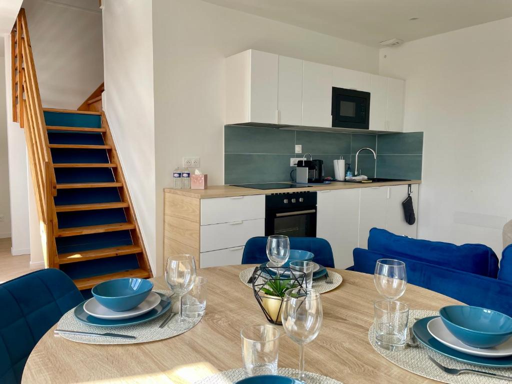 a dining room with a table and blue chairs at Duplex d Iroise rénové 2 chambres Centre Gouesnou Parking & Wifi in Gouesnou
