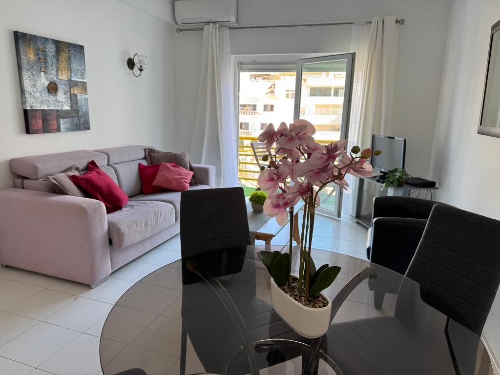 a living room with a couch and a table with a plant at Cerro Apartment in Carvoeiro