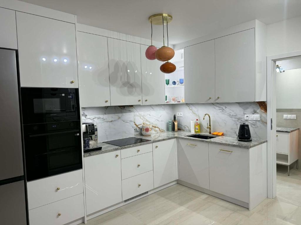 a white kitchen with white cabinets and a black refrigerator at Apartament Ablewicza VIP in Tarnów
