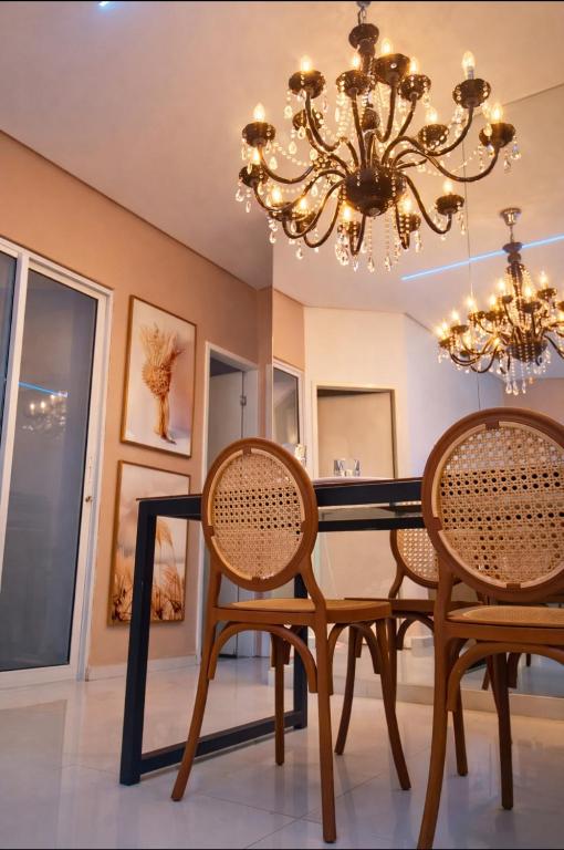 a dining room with a black table and chairs and a chandelier at Lua prime residence in Petrolina