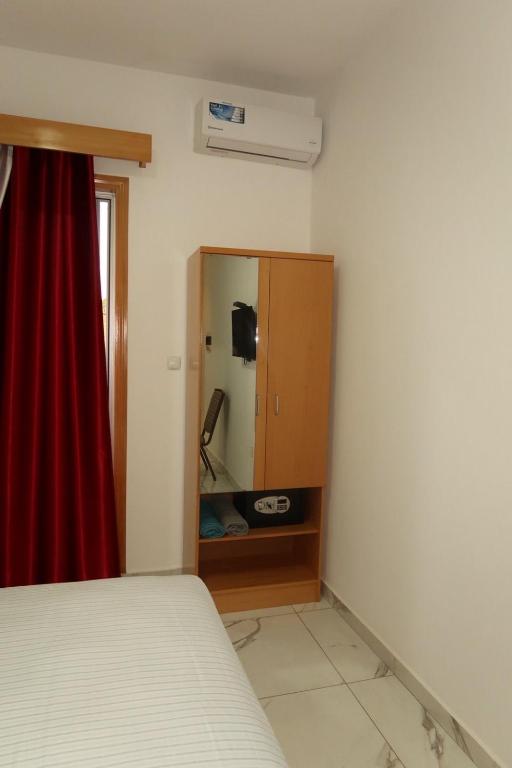 a bedroom with a bed and a cabinet with a mirror at Guest House RosAmado in São Filipe