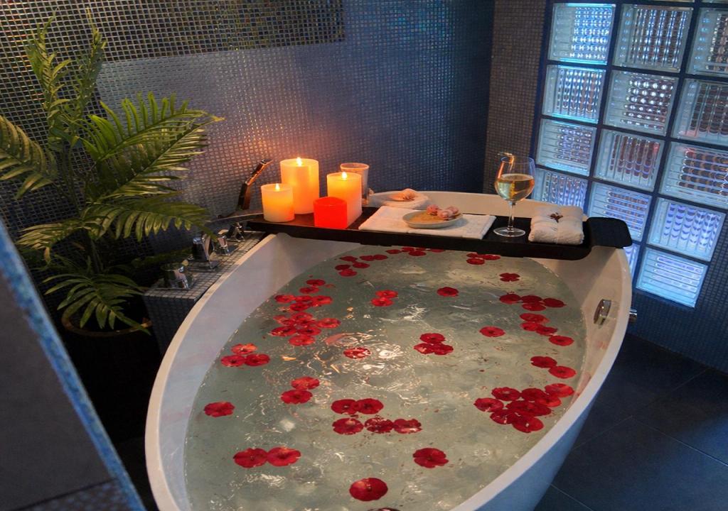 a bath tub filled with red flowers and candles at Asenata Apartament 46m2 Ustroń Centrum in Ustroń