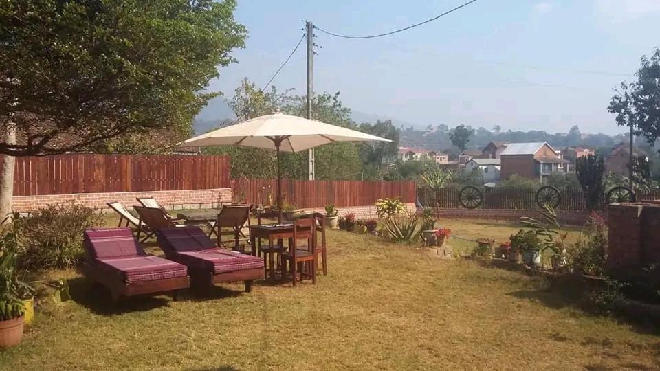 a table and chairs and an umbrella in a yard at Hotel Anjara in Ambositra