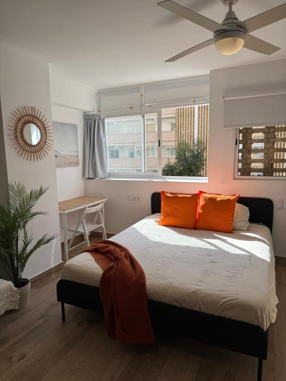 a bedroom with a bed with orange pillows and a ceiling fan at Ideal parejas Estudio Granadella en Jávea in Platja de l'Arenal