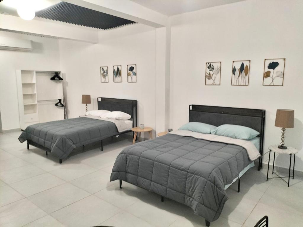 two beds in a room with white walls at Depa Loft Monterrey cerca de Fundidora, Macroplaza y Barrio Antiguo in Monterrey
