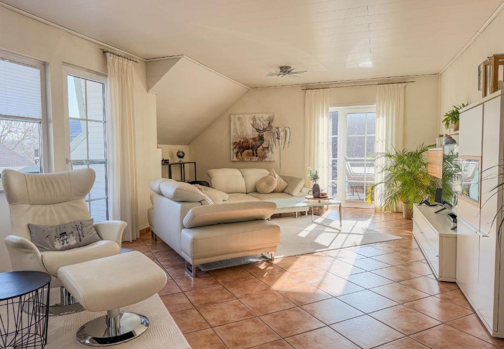 a living room with a white couch and chairs at Harz-Fewo Weitsicht, modern & ruhig mit 2 Balkonen, Jura Kaffeevollautomat, Kaminofen, Gäste mit Hund willkommen in Bad Harzburg