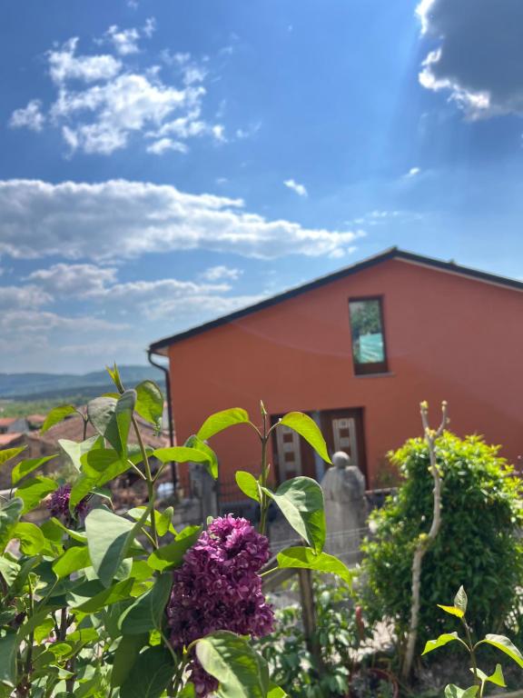 ein rotes Haus mit Blumen davor in der Unterkunft Nedi's Nest - Cozy Countryside Retreat Under Palmtrees in Dutovlje