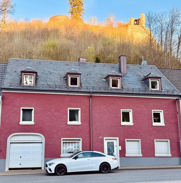 a white car parked in front of a red house at The red House in Schönecken