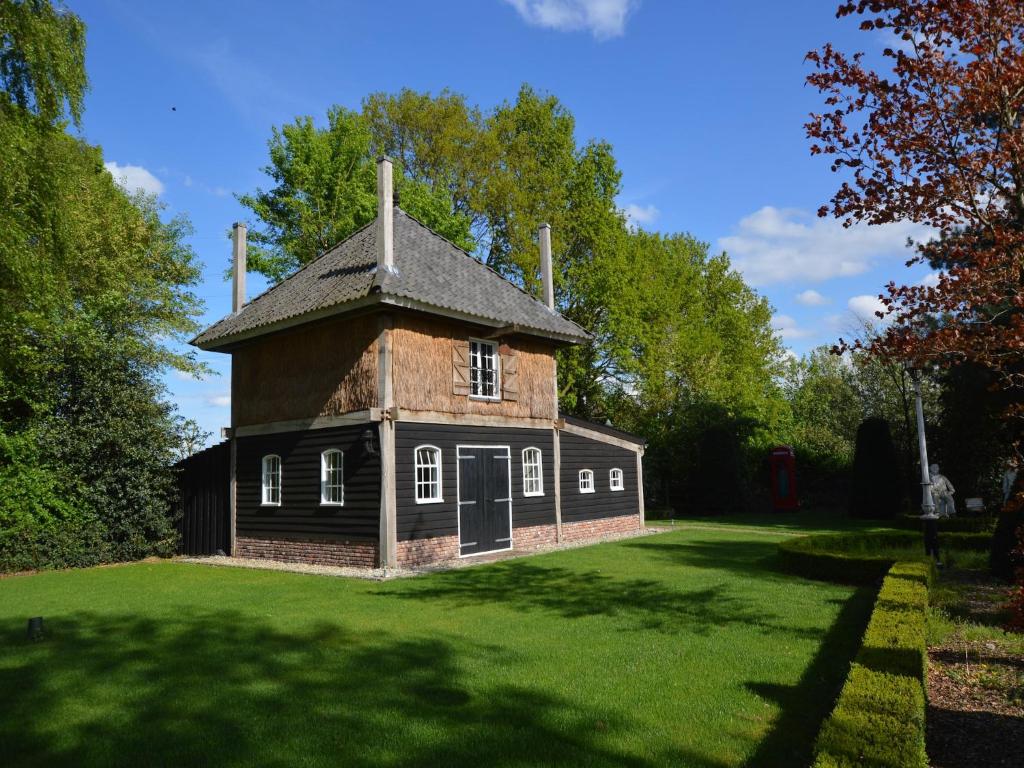 an old house on a grassy field with trees at Cozy holiday home in Volkel with Sauna in Volkel
