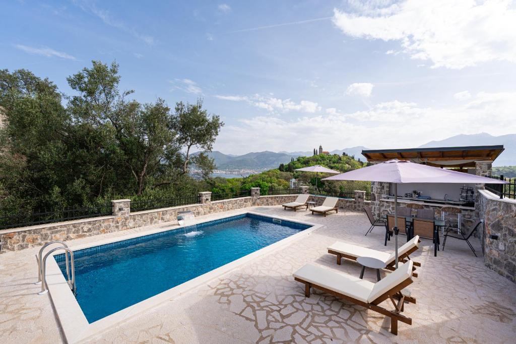 a swimming pool with chairs and a table and an umbrella at Casa Bellavista in Tivat