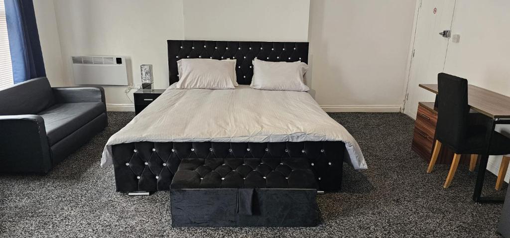 a bedroom with a bed with a black headboard and a couch at Liv's place in Oldbury