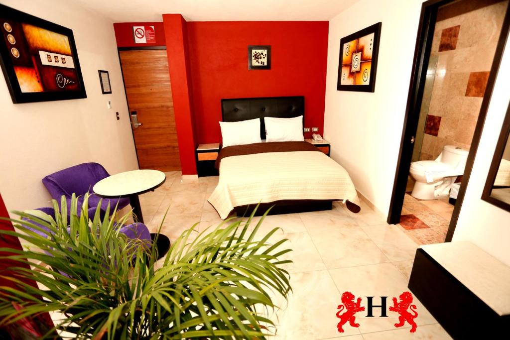 a bedroom with a bed with a red wall at Hotel Leones in Puebla