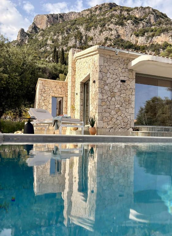a house with a swimming pool with a mountain in the background at Villa Xalupi - Design-Villa mit Pool und Meerblick in Paleokastritsa