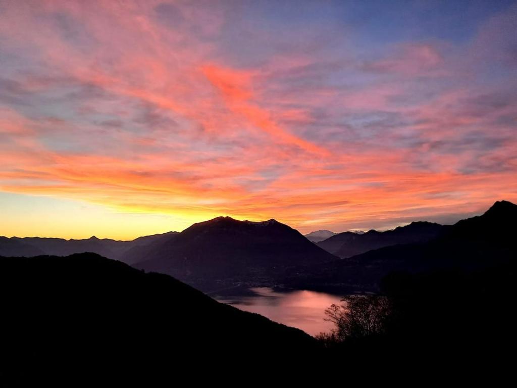a sunset over a mountain range with a lake at Chalet La Terrazza Vista Lago in Bellano