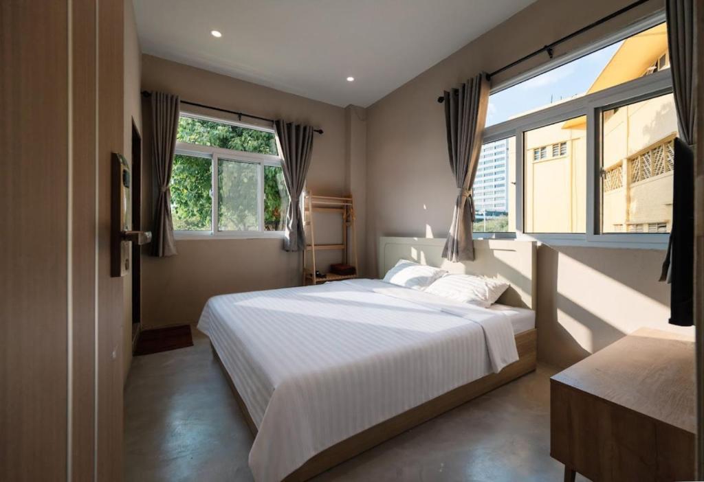 a bedroom with a large bed and two windows at Kosin House in Bangkok