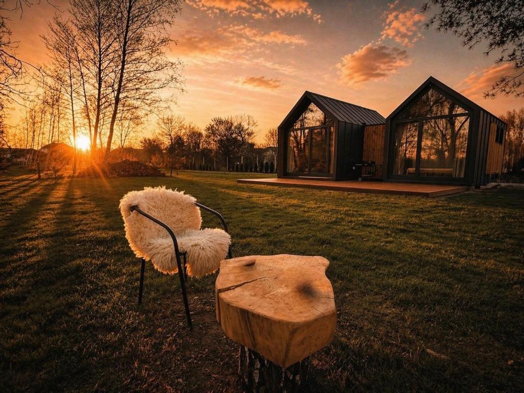 a couple of chairs sitting in a field with the sunset at RiverHouse in Bałtów
