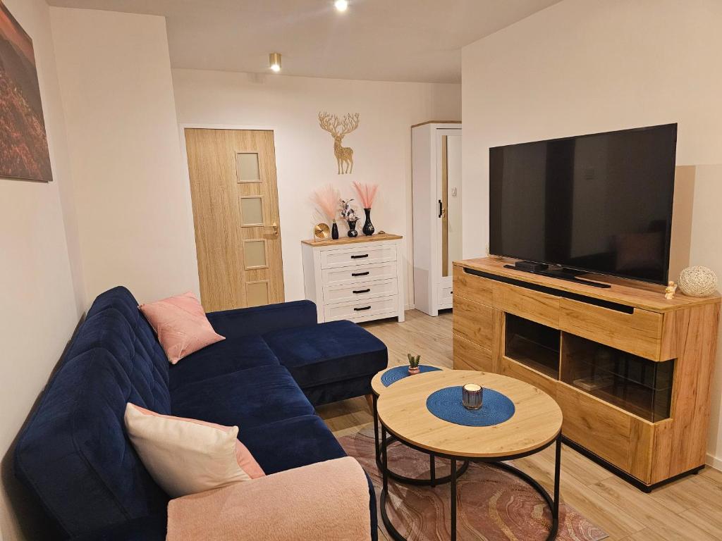 a living room with a blue couch and a flat screen tv at Szybowcowa View Apartment in Jelenia Góra