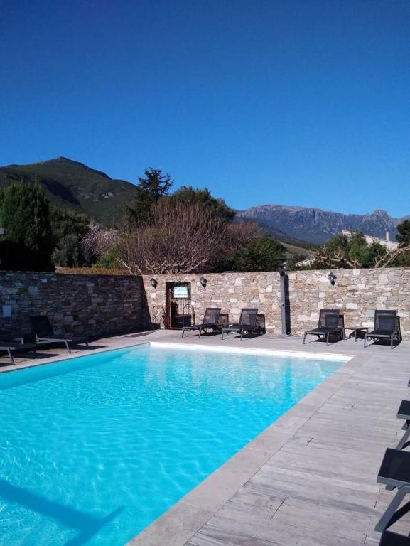 a swimming pool with chairs and a stone wall at Studio N 02 Stalla Sischese in Sisco