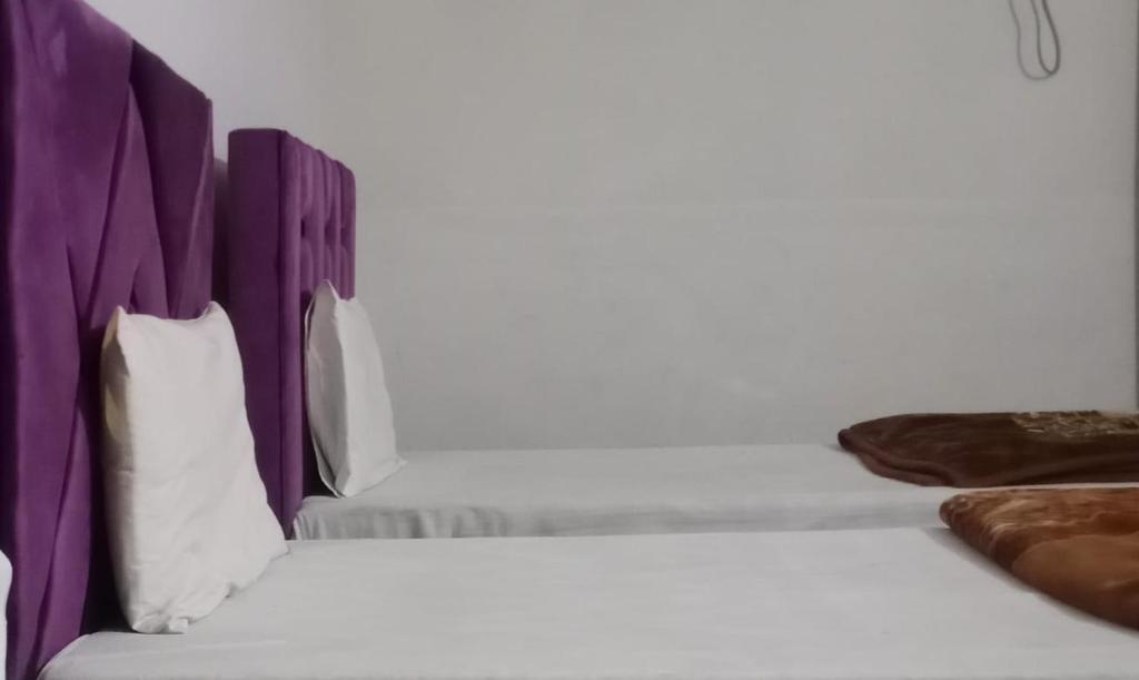 a bedroom with two beds with purple headboards at Eden Plus Executive Hotel Lahore in Lahore
