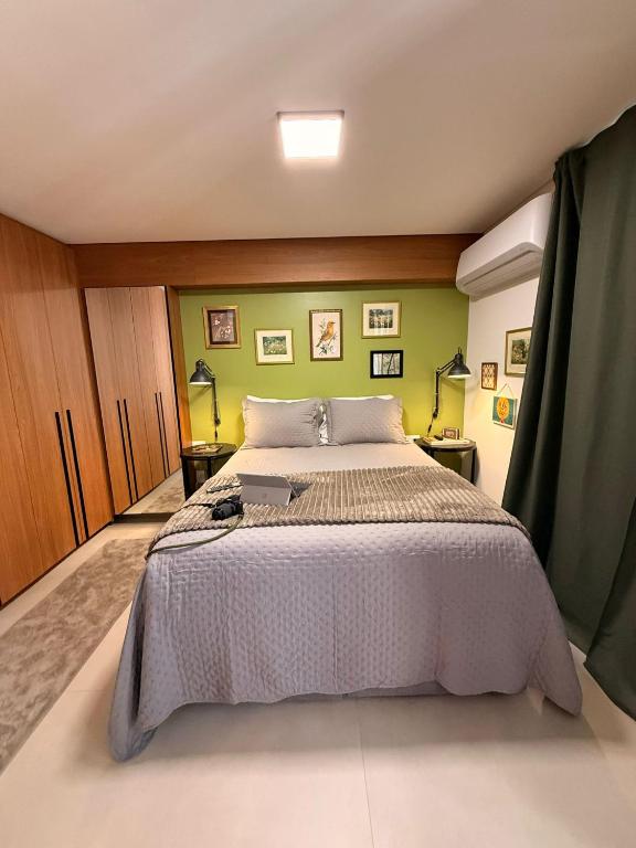 a bedroom with a large bed and a green wall at Apartamento 1 quarto Goiânia in Goiânia
