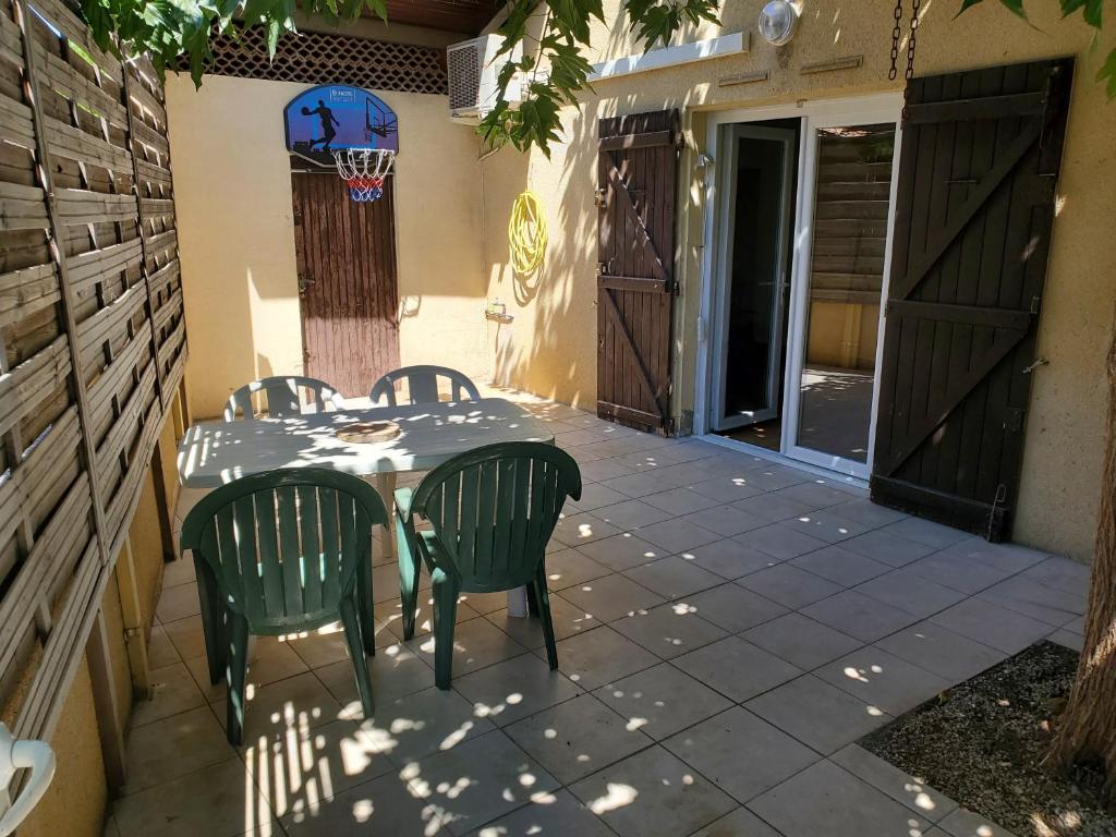 a patio with a table and chairs and a basketball hoop at maison individuelle in Le Grau-du-Roi