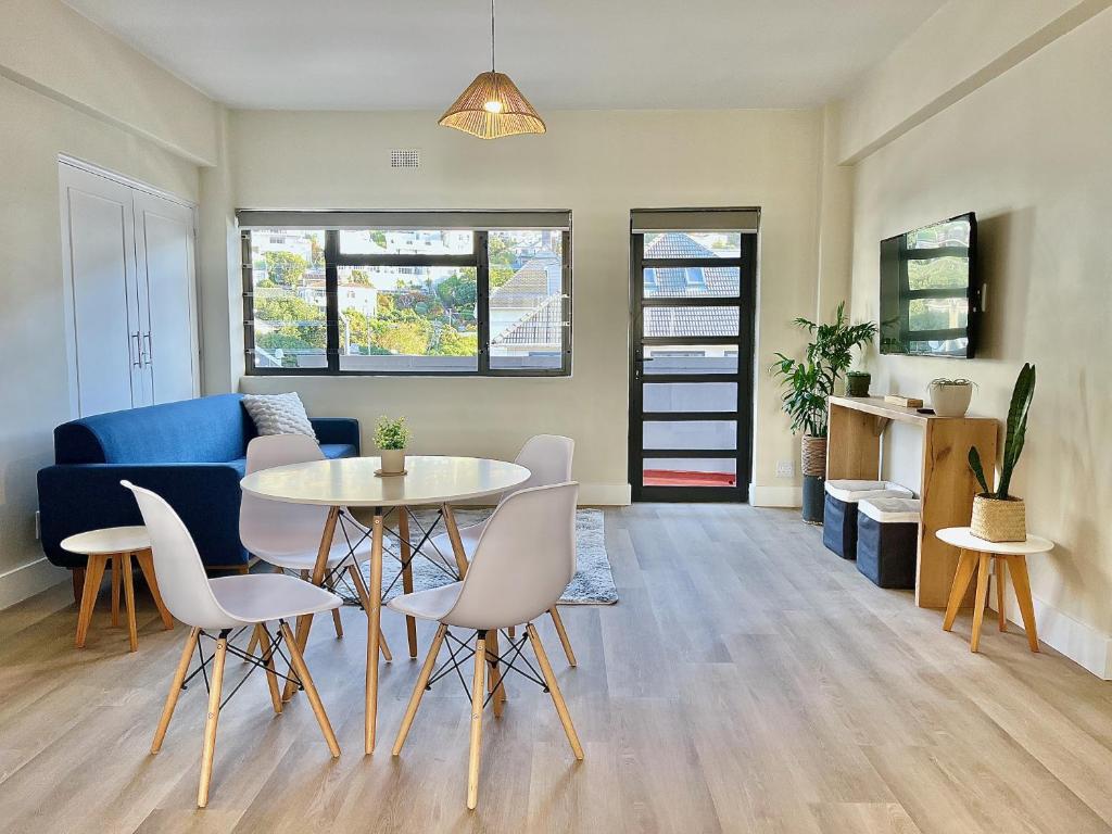 a living room with a table and chairs and a couch at Modern Seaside Apartment in Fish Hoek