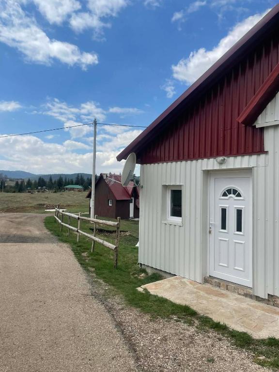 a red and white barn with a white door at Petrovica in Aluga