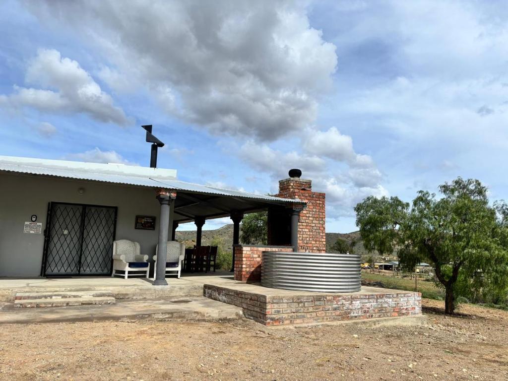 a brick house with a roof and a patio at Gamtoosberg Cottage in Oudtshoorn