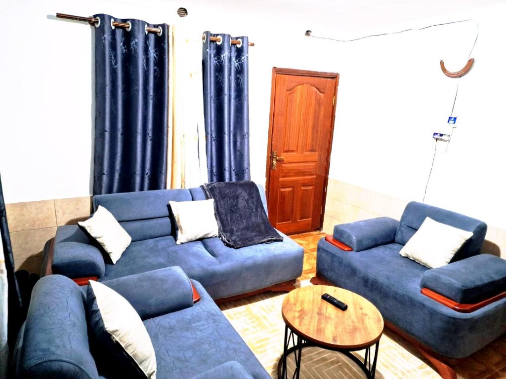 a living room with two blue couches and a table at Cosmic homes Ruiru Kimbo in Ruiru