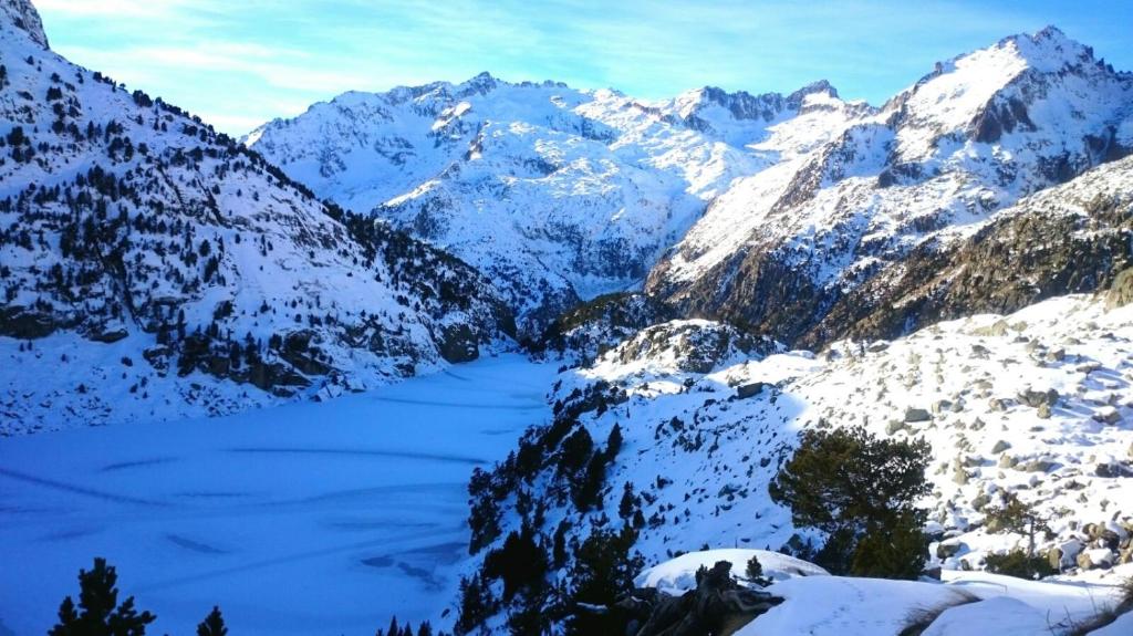 a snow covered mountain range with a river in the foreground at Sisquet Apartaments in Erill la Vall