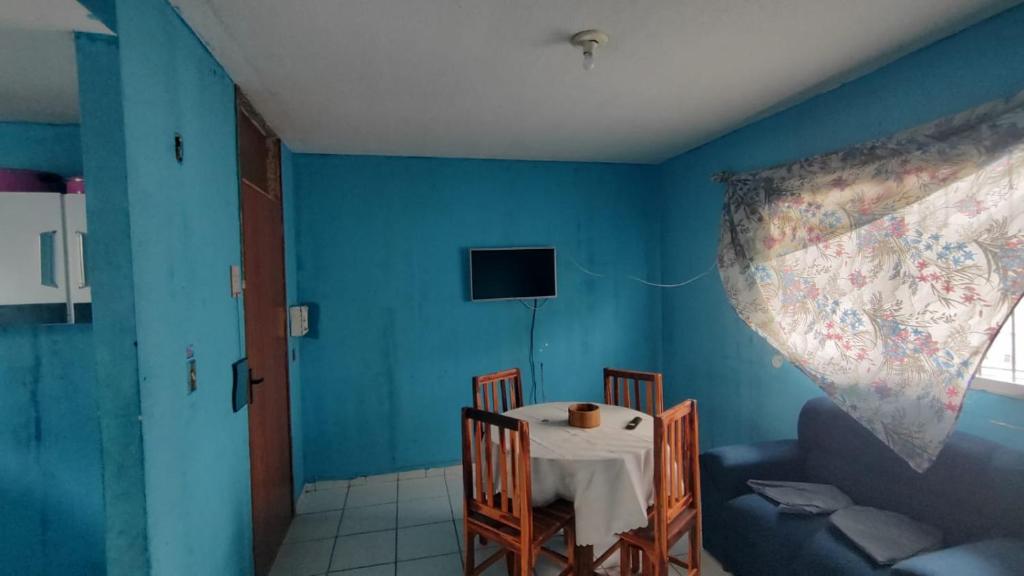 a dining room with a table and a blue wall at Conforto in Maricota
