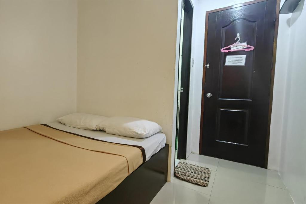 a small room with a bed and a black door at Liane's Place Puerto Princesa in Puerto Princesa City