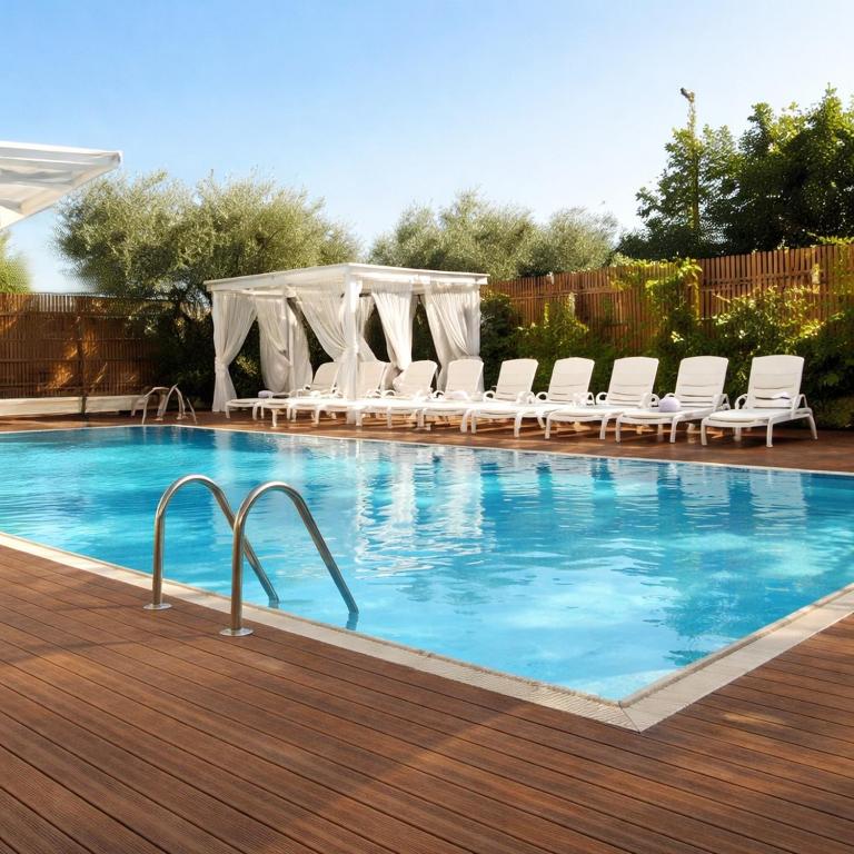 a swimming pool with chairs and a gazebo at Bellariva appartamenti in Rimini