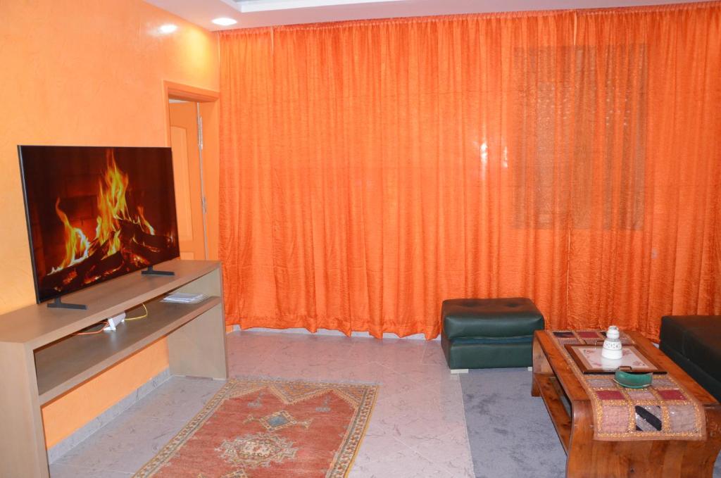 a living room with an orange curtain and a tv at Residence 33 orange in Guelmim