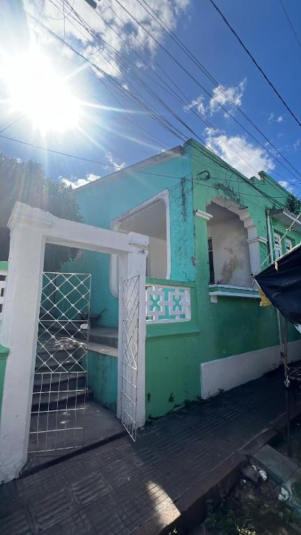 a green and white house with the door open at Pousada Oliveira in Cachoeira