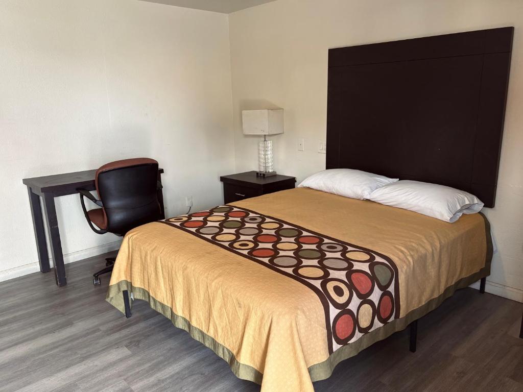a bedroom with a bed and a desk and a chair at Border Motel in Calexico