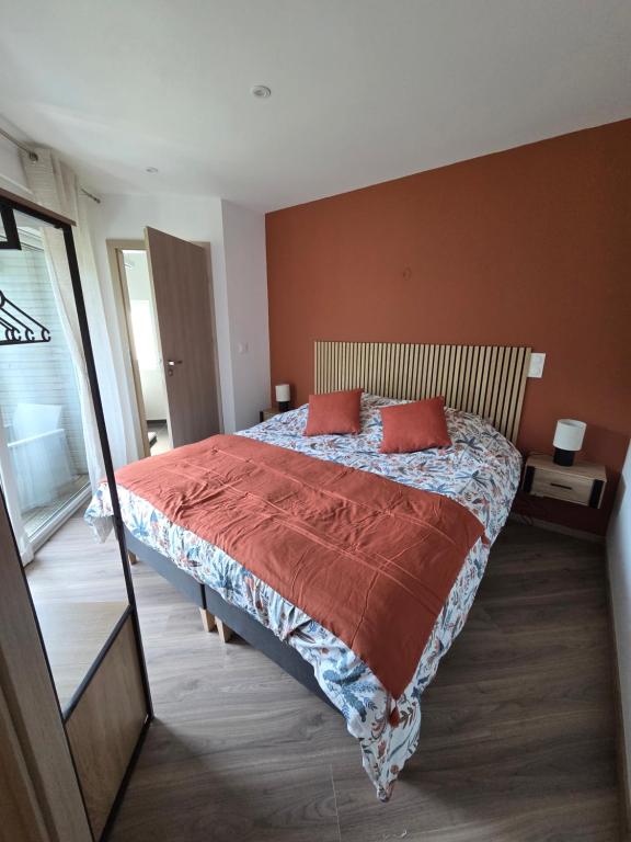 a bedroom with a bed with two red pillows at Le Petit L Orée des Bois in Blainville-sur-lʼEau