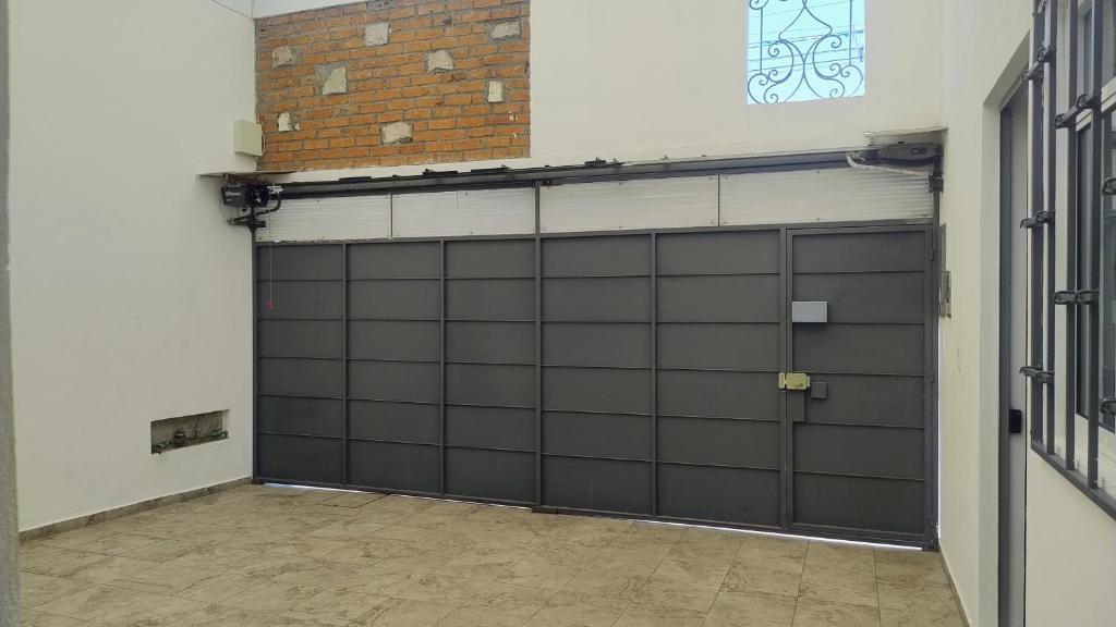 a garage with two garage doors and a brick wall at Habitación independencia in Morelia