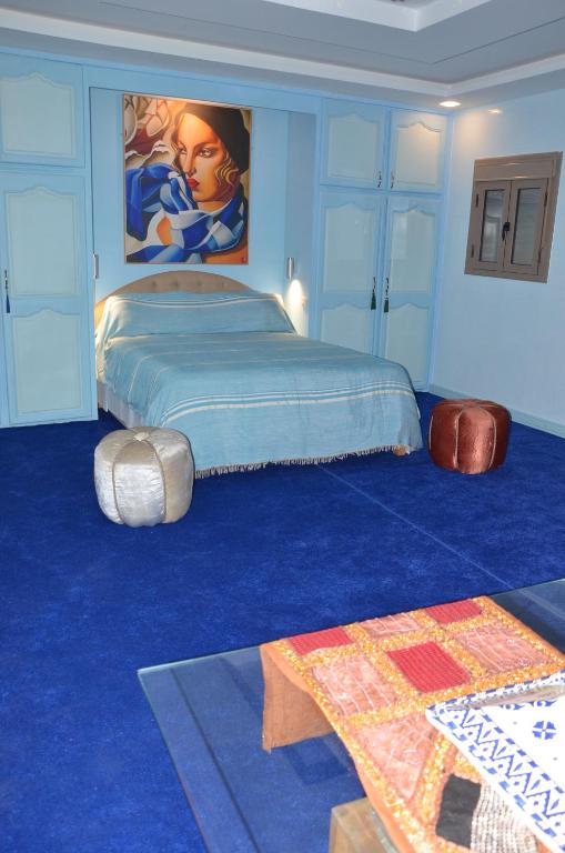 a bedroom with a large bed with a blue carpet at Residence 33 bleu in Guelmim
