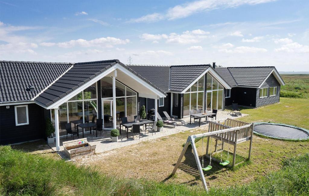 a house with glass doors and a playground at Nice Home In Ringkøbing With Sauna in Ringkøbing