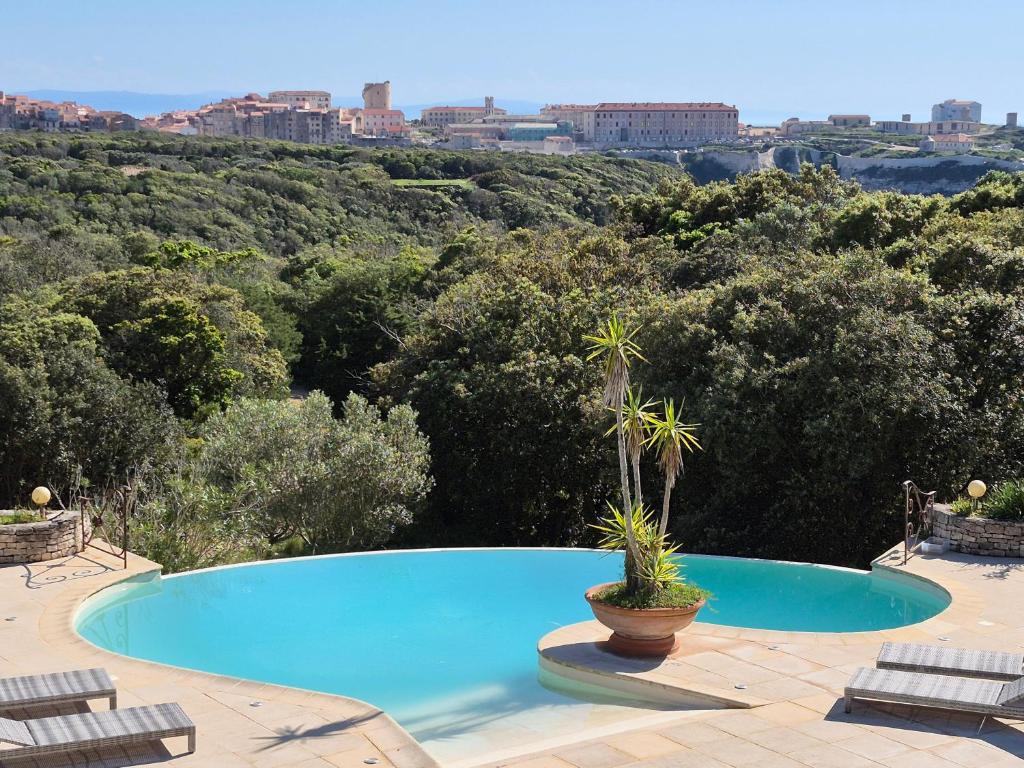 a swimming pool with two chairs and a view of the city at Villa A Macchia, piscine et vue sur Bonifacio in Bonifacio