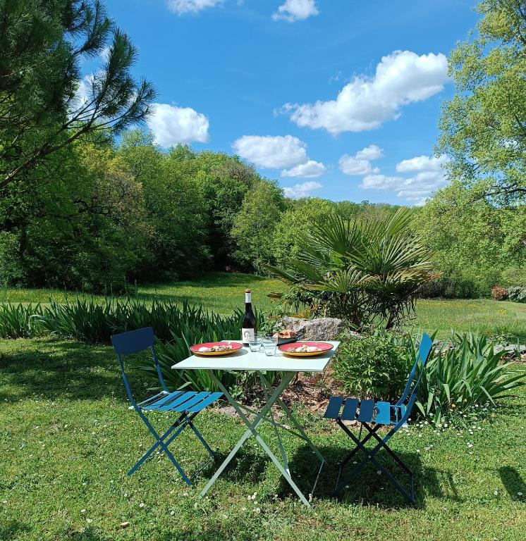 a table with a bottle of wine and two chairs at Une escale gourmande- Suite avec terrasse & dîner maison possible in Eyzerac
