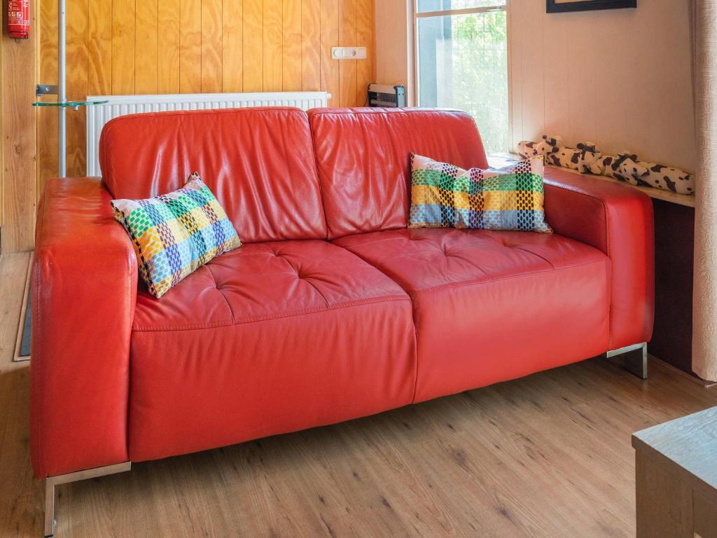 a red leather couch with two pillows on it at Cottage in Dwingelderveld with Scenic Views in Beilen