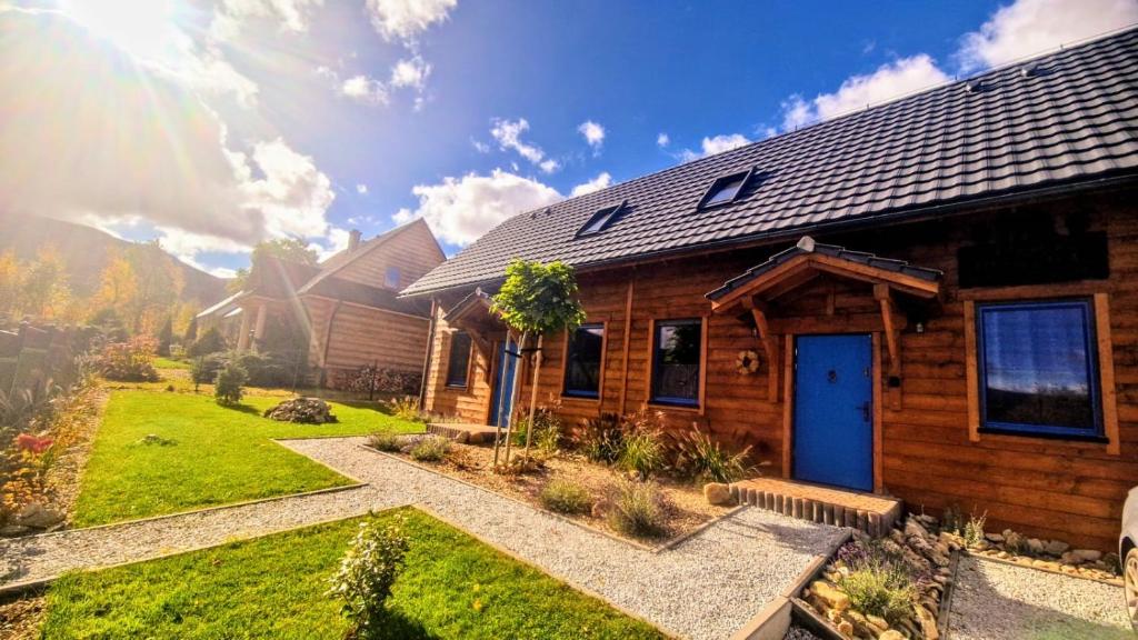 a log home with a blue door and a yard at Chata Bławatek Kowary in Kowary