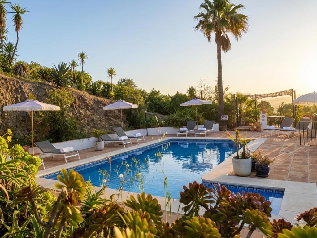 a swimming pool with chairs and umbrellas on a resort at Finca Flamenco Holiday Suites Adults Only in Pizarra