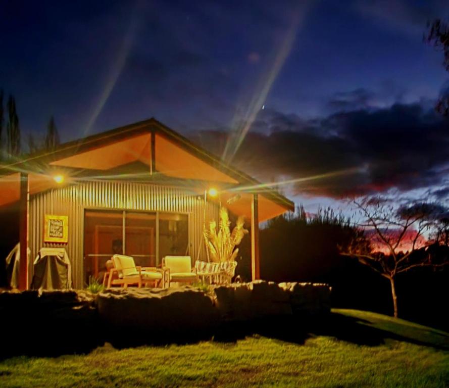 a house with a table and chairs in front of it at Ripples Retreat - Riverside Luxury in Piopio